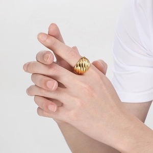 Gros plan d'une bague croissant dorée montrant une texture en spirale sur un doigt