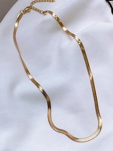 Close-up of golden herringbone snake chain necklace with lobster clasp on white fabric