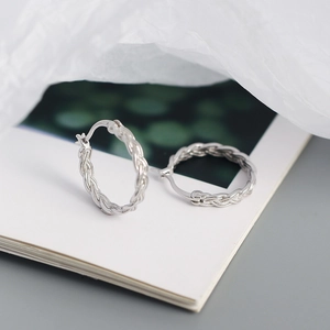 Detailed view of silver woven chain hoop earrings in a minimalist fashion layout