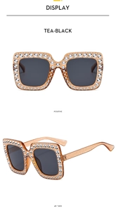 Detail view of tea-black square oversized sunglasses with sparkling crystal accents