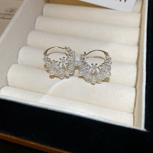 Detail of silver hollow basket hoop earring with white pearls in jewelry box