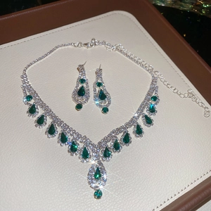 Macro shot of silver bridal necklace and emerald teardrop earrings on display tray