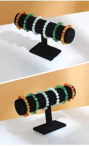 Detailed view of three jade bead bracelets in various colors on a black T-bar display stand