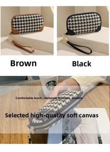 Detail of high-capacity houndstooth canvas clutch bags in brown and black with wrist straps