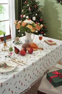 Detailed view of white cotton Christmas tablecloth featuring festive berry prints and ruffles
