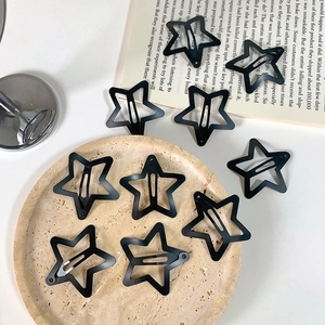 Set of 10 matte black star shaped metal hair clips in y2k aesthetic on a stone background