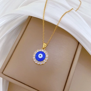 Gold Evil Eye necklace with blue center and CZ crystals on elegant white silk background