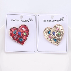 Detailed comparison of red enamel and gold textured heart brooches with colorful rhinestones