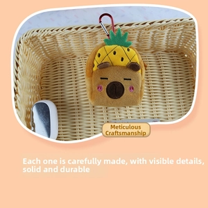 Detail of Capybara plush mini bag with yellow pineapple hat and red metal carabiner clip