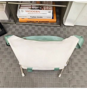 Close-up of off-white nylon crossbody bag with light green strap and buckle details