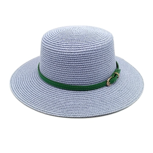 Détail du chapeau de paille tissé avec ruban en cuir vert et boucle en métal brillante