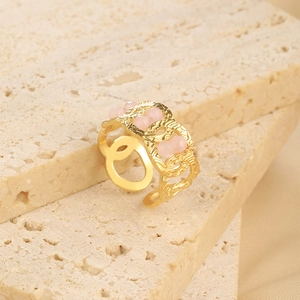 Detail view of gold chain link ring featuring four elegant pink beads on stone surface