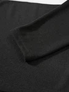 Vue macro de la maille fine et du détail des poignets sur un pull vintage noir