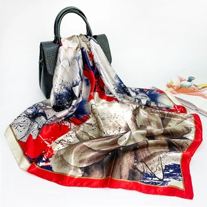 Detail of a floral satin square scarf draped elegantly on a black crocodile leather handbag