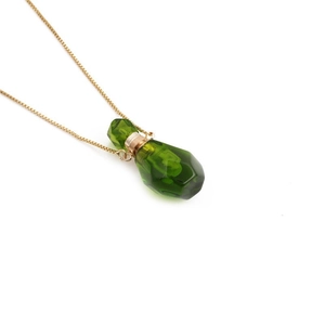 Macro shot of green aventurine flame-shaped perfume bottle pendant on gold chain