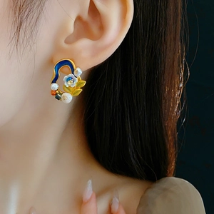 Detail of vintage flower earrings with blue enamel, freshwater pearls on a model