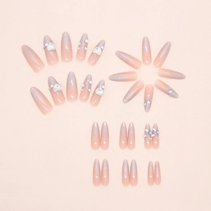 Detail of almond cat-eye press-on nails with 3D white flowers and pearl ornaments