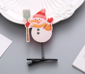 Detail einer glitzernden Schneemann-Haarklammer mit Feder und rotem Hut für Kinder