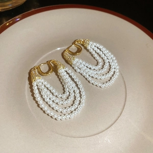 Détail macro de boucles d'oreilles à perles multicouches avec finition dorée et zircon