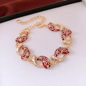 Close-up of vintage gold bracelet with red enamel flowers and clear zircon pendants