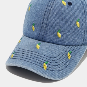 Detail of yellow lemon embroidery on high-quality blue denim fabric baseball cap