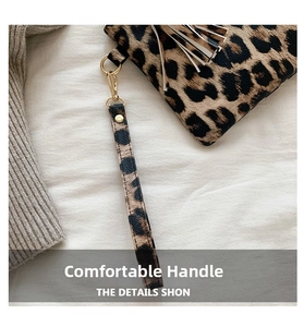 Detail view of leopard print clutch bag with golden tassel and detachable wrist strap