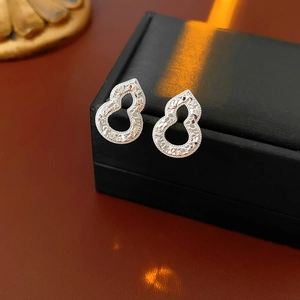 Macro detail of silver gourd earrings with textured finish on a black jewelry box