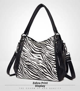 Close-up of zebra print handbag featuring black lychee leather trim and metal zippers