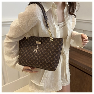 Detail of vintage brown tote bag with geometric pattern, chain strap and deer pendant