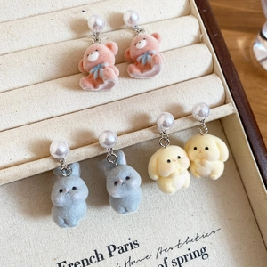 Macro shot of flocked bear and rabbit stud earrings with pearls in a jewelry box