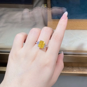 Macro detail of radiant cut yellow gemstone ring with side trapezoid diamonds on hand
