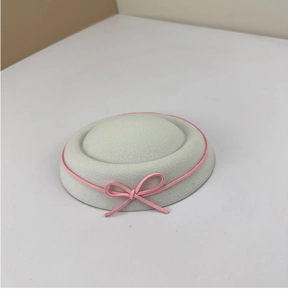 Detail of white wool felt beret featuring delicate pink rope and elegant bow decoration