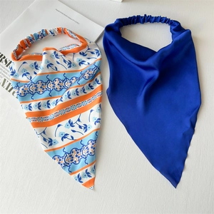 Detail of silk-like elastic headbands in floral print and solid royal blue colors