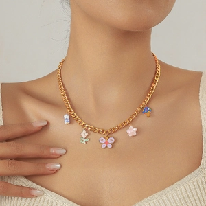 Collier chaîne dorée avec pendentifs papillons et fleurs colorés porté par un mannequin