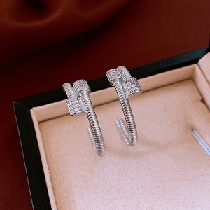 Detailed close-up of silver C-shaped nail earrings with sparkling zircon stones in a gift box
