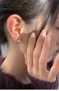 Primer plano de pendientes de nudo dorados con textura de espiral usados por modelo