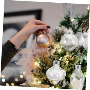 Main accrochant une boule de Noël dorée champagne sur un sapin de Noël décoré