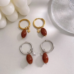 Détail de boucles d'oreilles pendantes ovales en grès doré et argenté sur fond blanc