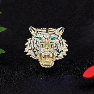 Détail macro d'une broche tête de tigre dorée avec diamants et yeux verts