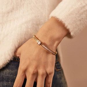 Detail of gold bracelet with rectangular crystal and white shell inlay on model wrist