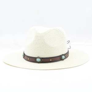 Dettaglio cappello di paglia con cinturino in pelle marrone, pietra turchese e borchie
