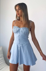 Détail d'une robe bleu clair à bretelles avec plis froncés et boutons décoratifs