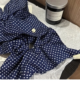 Detailed close-up of navy blue polka dot fabric texture with a single cream round button