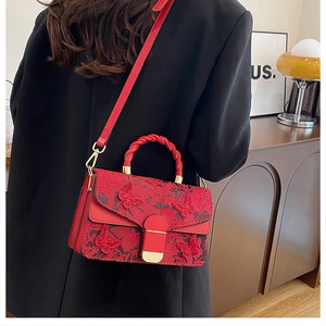 Détail du sac rouge à broderie papillon avec poignée torsadée et fermoir doré