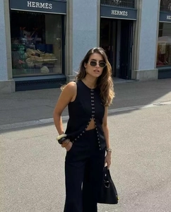 Detail of the chic black sleeveless vest with hook-and-eye closure and straight-leg pants