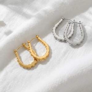 Textured U-shaped gold and silver hoop earrings with a wavy metal ripple design