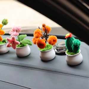 Close-up of handmade pipe cleaner sunflowers and mini potted plants on a car dashboard