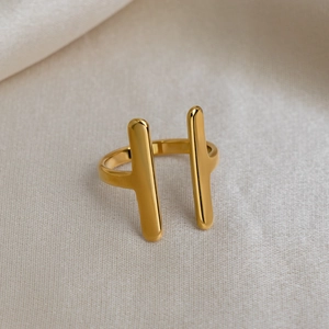 Detailed view of golden double-bar stainless steel ring on white satin fabric