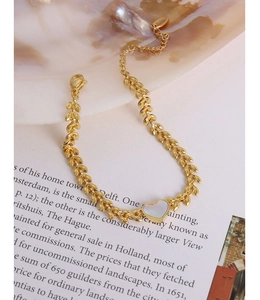 Detail of 18K gold wheat chain bracelet featuring a white heart mother of pearl pendant