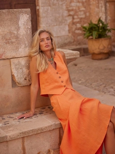 Detail of orange linen vest and maxi skirt set with natural texture in sunlight